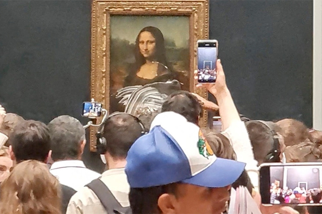 Man dressed as old woman throws cake at Mona Lisa painting